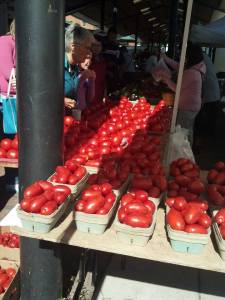 Photo of tomatoes lining a table at a farmer's market.