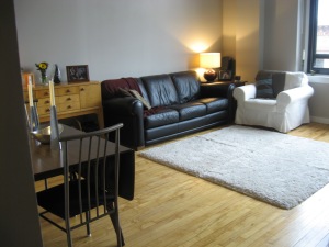 Photo of a living room with leather sofa, and dining table and chairs.
