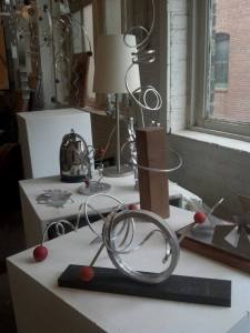 Metal table top and hanging sculptures by Caprice Glaser, displayed by a window in her stuido.