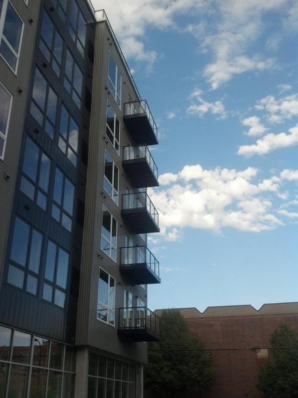 Photo of apartment building with blue sky and white clouds overhead.